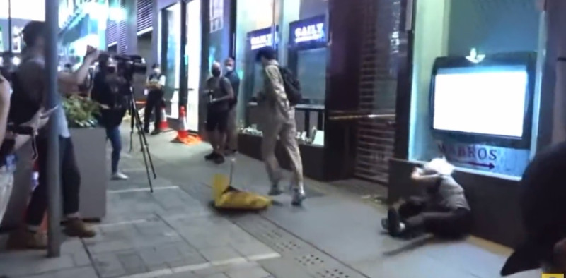 黃婆婆舉起象徵2014年雨傘革命的黃色雨傘時，被一名男子奪走雨傘，還被推跌躺在地上。   圖：推特