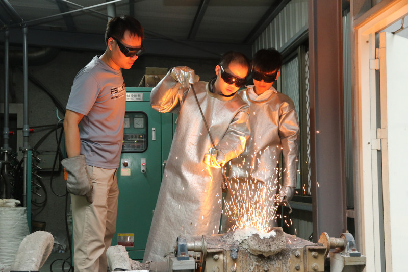 李佳峻（左）與尤正維（右）示範煉鋼過程，興大材料系博士後研究員林啟明指導。   圖：由中興大學提供