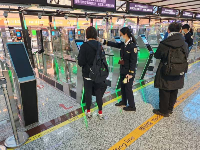 移民署執勤人員引導旅客使用自動查驗通關系統。   圖：內政部提供