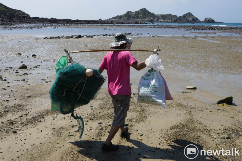 農曆十五前後的大退潮，鄭玉貴扛著章魚籠和漁網，在他家前面的潮間帶放網。   圖：張良一/攝