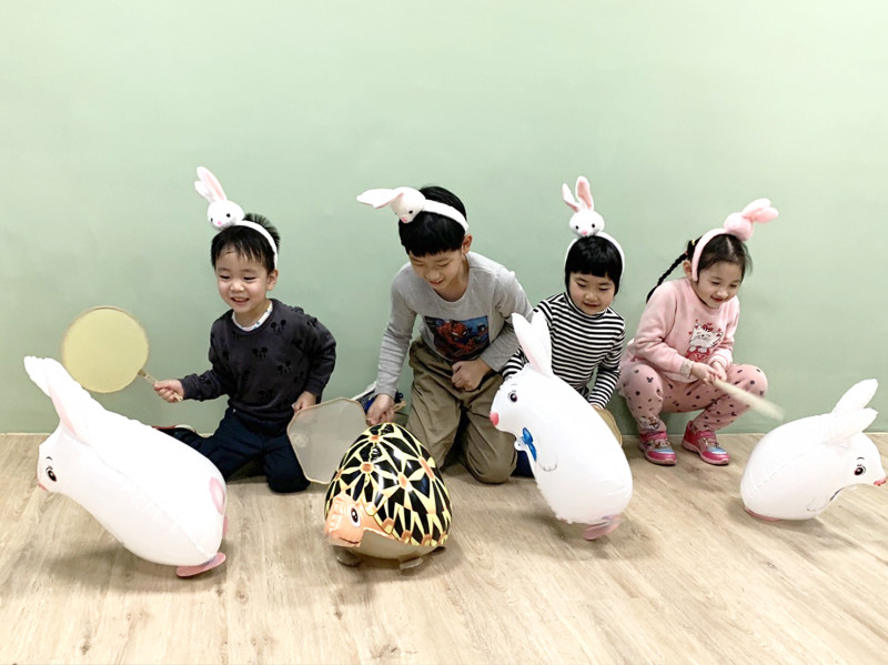 小朋友開心拿扇子搧動氣球前進玩龜兔賽跑遊戲。   圖：新北市文化局提供
