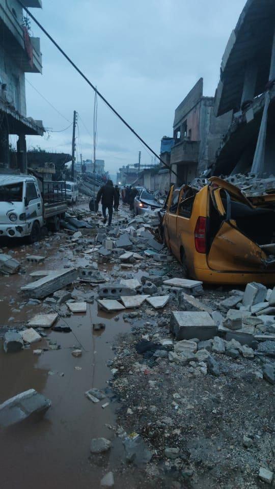 因地震造成街道兩旁的房屋損毀，連帶使停靠路邊的車輛被瓦礫砸毀。   圖：世界展望會提供
