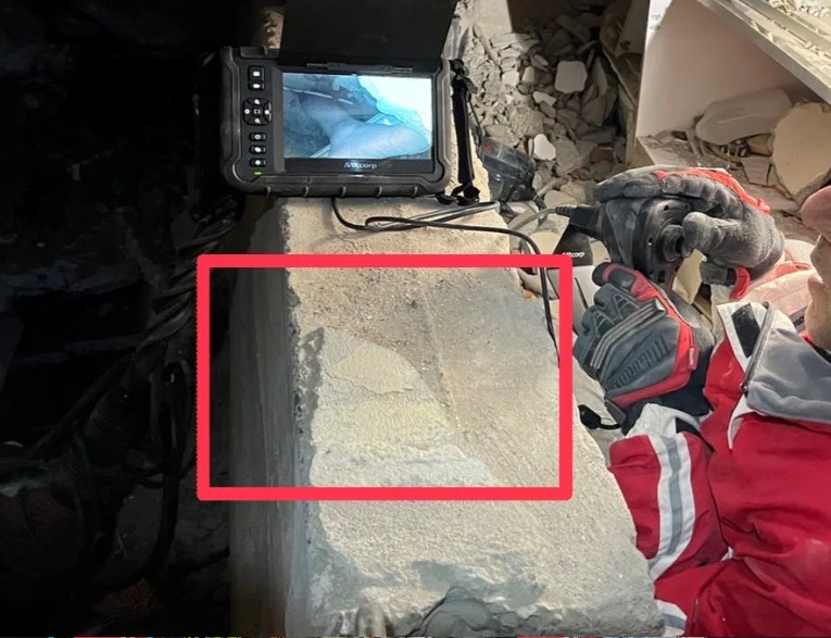 台灣救援隊伍與土耳其救援隊合作執行任務時，發現1名民眾受困在水泥柱下，並露出腳。   圖：消防署提供