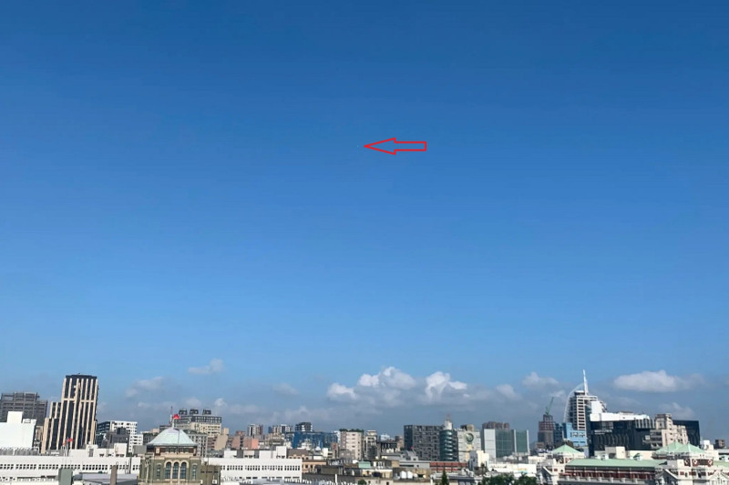 美國媒體《紐約時報》引用中央氣象局局長鄭明典照片，指2021年9月27日上午8時29分晴空萬里下台北市景中，有一個「小白點」是一個來源不明的高空氣球。   圖：翻攝鄭明典臉書