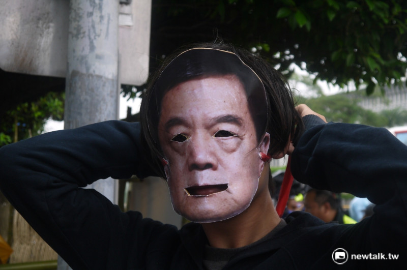 陳抗民眾正戴上徐旭東面具。   圖：鍾孟軒/攝