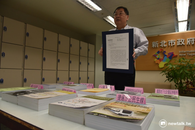 捷運局長趙紹廉手中拿著公文，桌面上則是送交審查的軌道計畫。   圖：新北市政府提供。
