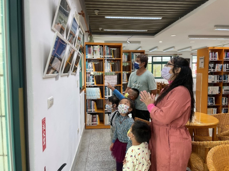 幼兒邀請家長到圖書館觀賞攝影展並熱情解說。   圖：新北市教育局提供