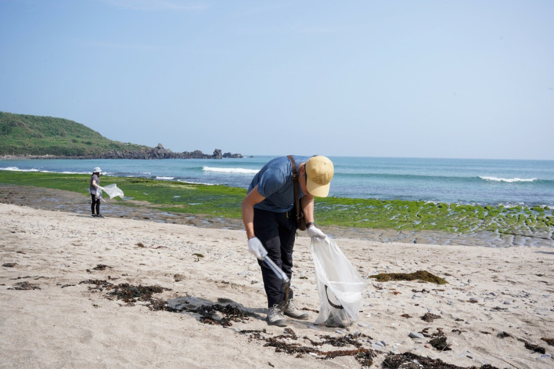 民眾在石門老梅綠石槽沙灘清理海岸垃圾。   圖：新北市環保局提供