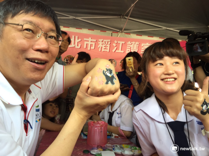 台北市長柯文哲今天出席「第五屆愛天使樂活園遊會」，稻江學生在柯文哲手背上，畫上世大運吉祥物熊讚圖像，柯文哲還因手癢而不時竊笑。   圖：林人芳／攝