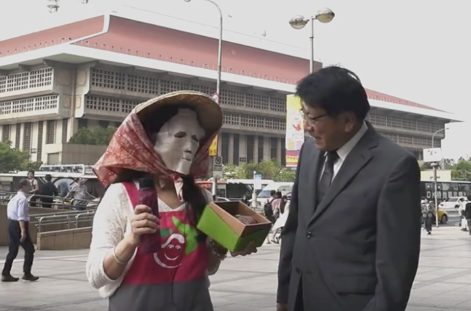 屏東縣長潘孟安在台北街頭遇到一位面膜「怪客」，向自己兜售屏東農產品。   圖：翻攝自屏東縣政府宣傳影片