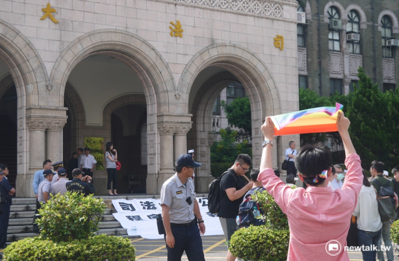 臺灣大學法研所學生獨自一人前往司法院高舉彩虹旗支持同性婚姻法案。   圖：鍾孟軒/攝