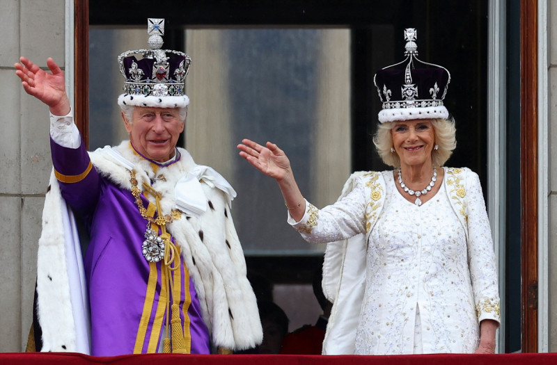 英王查爾斯與王后卡蜜拉與民眾揮手致意，並觀看空中分列式。   圖：路透社