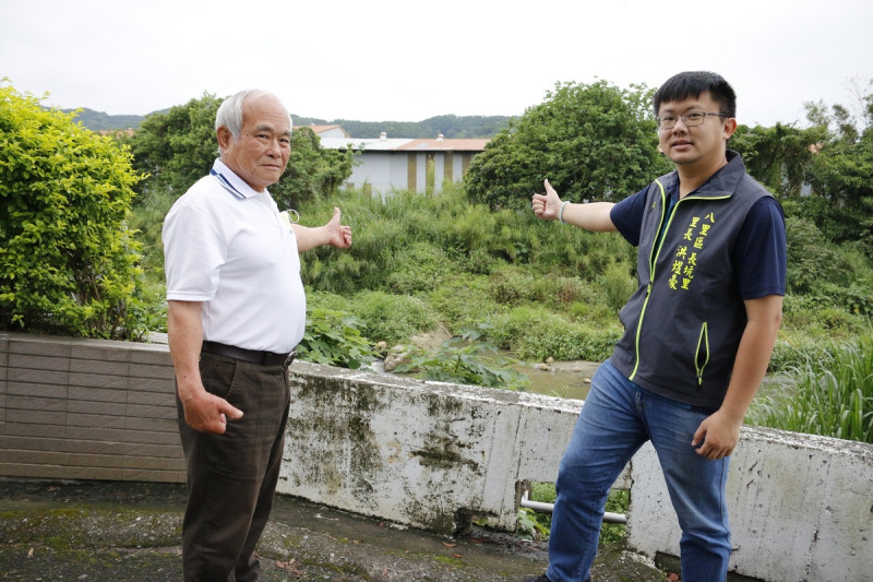 八里區長坑里前後任里長洪啟誠、洪煜豪於正名後的紅水仙溪前合影。   圖：新北市水利局提供