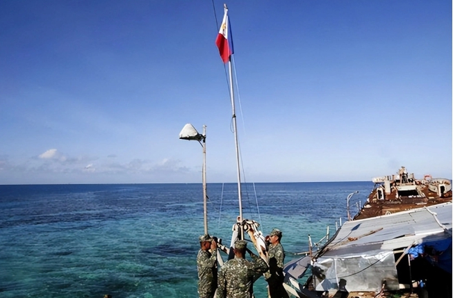菲律賓部隊在南海仁愛礁擱淺的船隻上升起國旗，宣示主權。   圖 : 翻攝自騰訊新聞/俯瞰全球