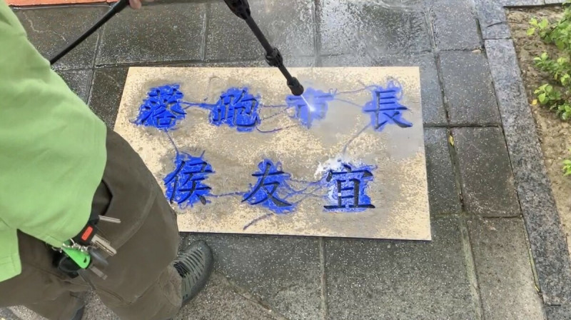 公投護台灣聯盟成員在新北市政府前進行洗地板行動，並洗出「落跑市長侯友宜」字樣抗議，被警車帶回派出所訊問。   圖：公投護台灣聯盟提供