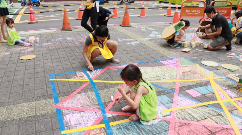 「街道遊戲實驗」是台灣還我特色公園行動聯盟帶領現場大小朋友，利用紙箱、線繩等素材在街道上佈置與遊戲，透過遊戲方式讓孩子們摸索街道空間，激發大小朋友對於人行環境的關心。   圖：新北市工務局提供