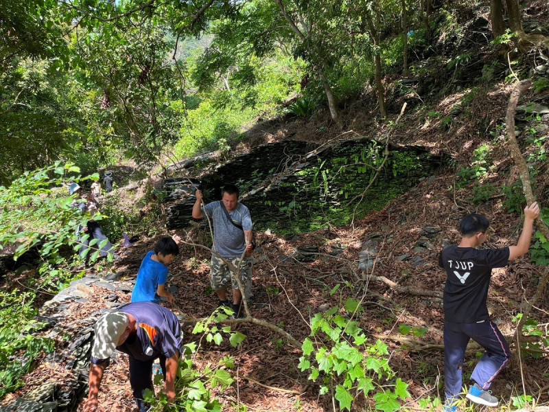 族人在石版屋舊遺址祖宅除草、整理環境。   圖：高雄市原民會/提供