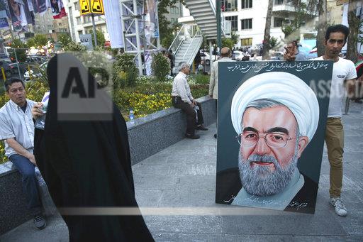 伊朗總統哈桑·羅哈尼（Jaassan Rouhani）的支持者在伊朗德黑蘭市中心拿競選看板。羅哈尼成功連任。   圖：達志影像/美聯社提供