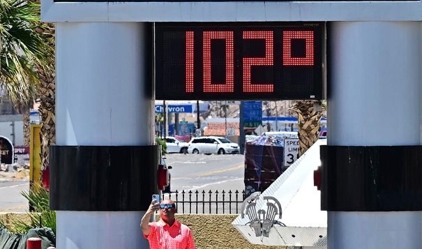 當地時間2023年7月11日，美國加州貝克，熱浪襲來，一名男子在溫度計旁自拍，溫度計顯示華氏102度（約攝氏38.8度）。   圖：翻攝自澎湃