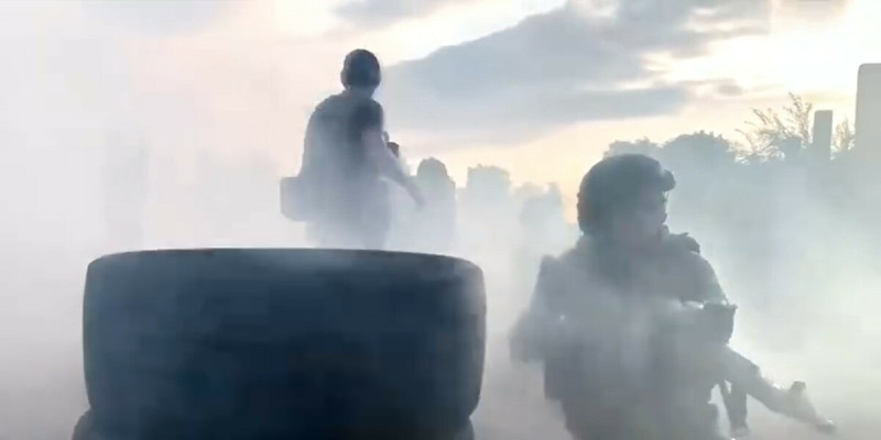 1 名接受訓練的女兵蹲在掩體旁，被現場煙霧嗆得咳嗽起來。   圖：翻攝自國防時報TV