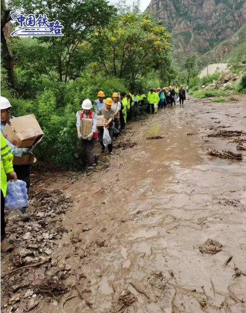 救難人員走過泥濘山路，將物資送到受困的K396火車旅客手中。   圖 : 翻攝自中國鐵路網
