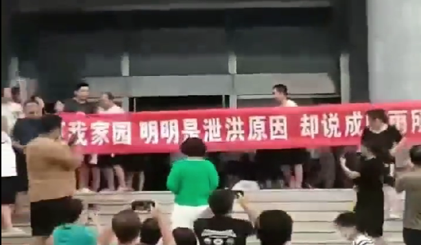 霸州居民在市政府前舉布條抗議，布條上寫著「還我家園，明明是洩洪原因，卻說成降雨所致」。 圖：翻攝自李老師不是你老師 X 平台