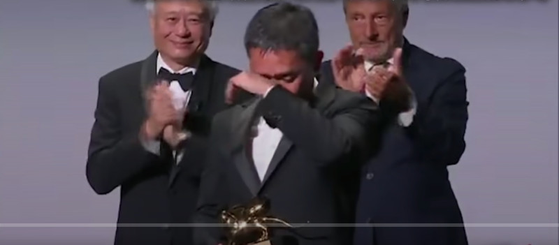 李安形容梁朝偉是「導演的夢想」，惹得他上台後激動落淚，打趣地向李安抱怨：「你就是想讓我哭。」   圖：擷取自第80屆威尼斯影展直播畫面