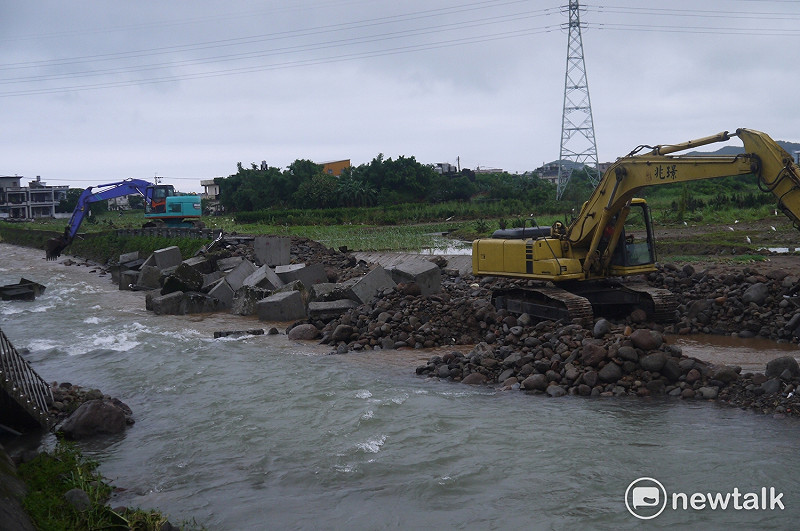 兩台怪手在清水溪旁努力把坍塌的堤防補起來。   圖：鍾孟軒/攝