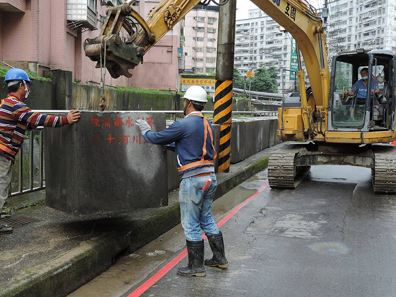 第十河川局隨即調動人員及機具，趕在當天晚上鋒面北移的第二波豪雨來襲時，連夜緊急在河道旁人行道上堆疊1公尺高的混凝土塊暫時封堵   圖:翻攝自自第十河川局官網