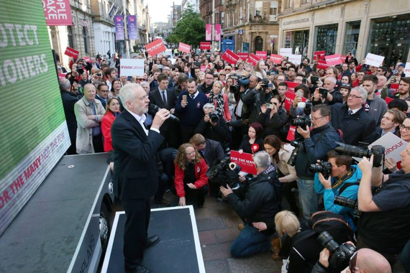 英國工黨在本次國會大選中民調上升，領袖柯賓（前排拿麥克風者）不敢大意，選情向支持者喊話。   圖：翻攝柯賓臉書