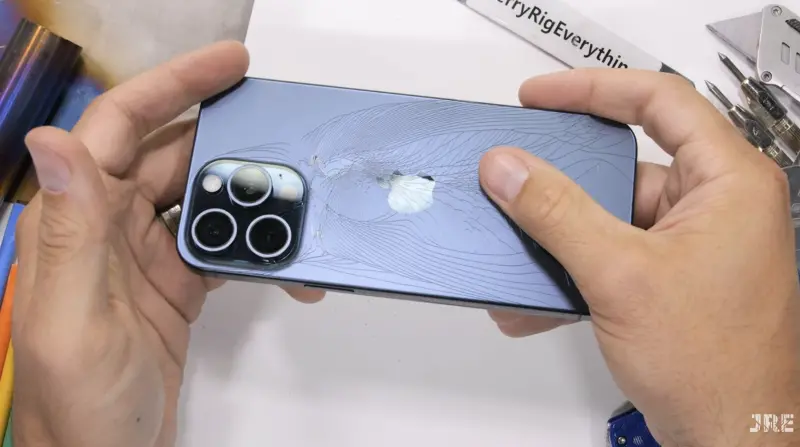 「JerryRigEverything」對iPhone 15 Pro Max進行一系列暴力測試，最終他徒手一折，發現機身玻璃背蓋應聲碎裂，佈滿密密麻麻的裂痕。   圖／翻攝自「JerryRigEverything」YT