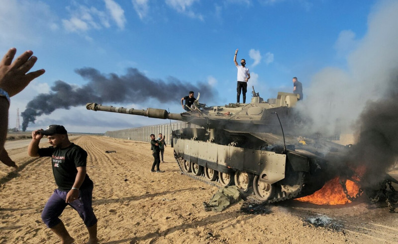 巴勒斯坦人在一輛被摧毀的以軍戰車上慶祝。   圖：美聯社／達志影像