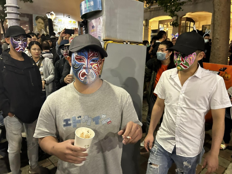 在28日晚間的新竹萬聖節大遊行中，一群畫上八家將臉譜的黑衣人將提款機團團包圍。   圖：擷自臉書「新竹市新政治」