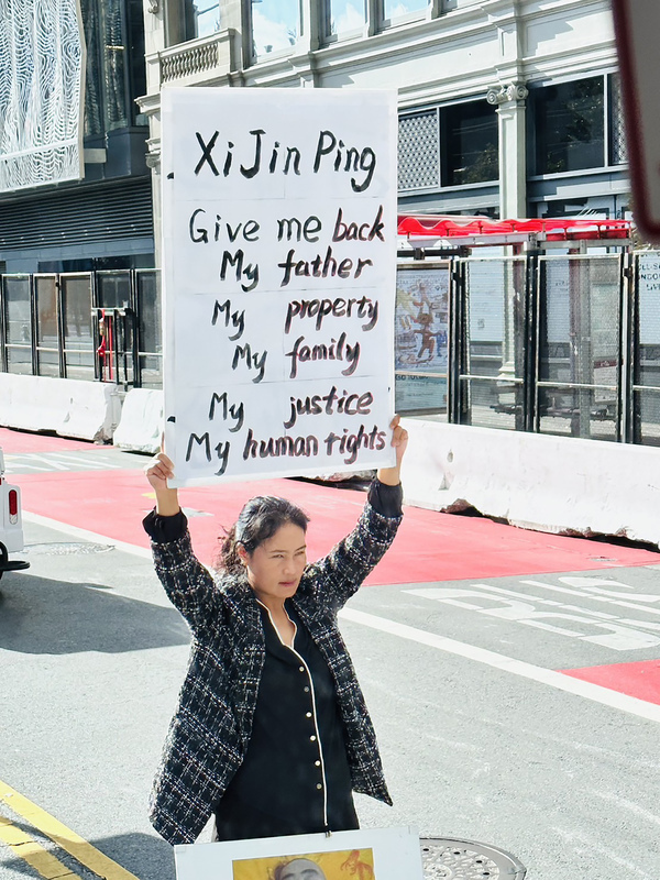 亞太經濟合作會議（APEC）11日展開，會場附近有一名來自中國黑龍江的女子高舉「習近平還我財產、還我家園、還我父親」標語牌，表達訴求。   圖：APEC台灣媒體團提供