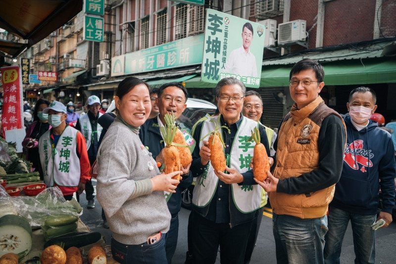 金曲歌王楊烈陪同民進黨新北市三重立委參選人李坤城市場造勢，攤商贈送蘿蔔象徵「好采頭」。   圖：李坤城競總提供