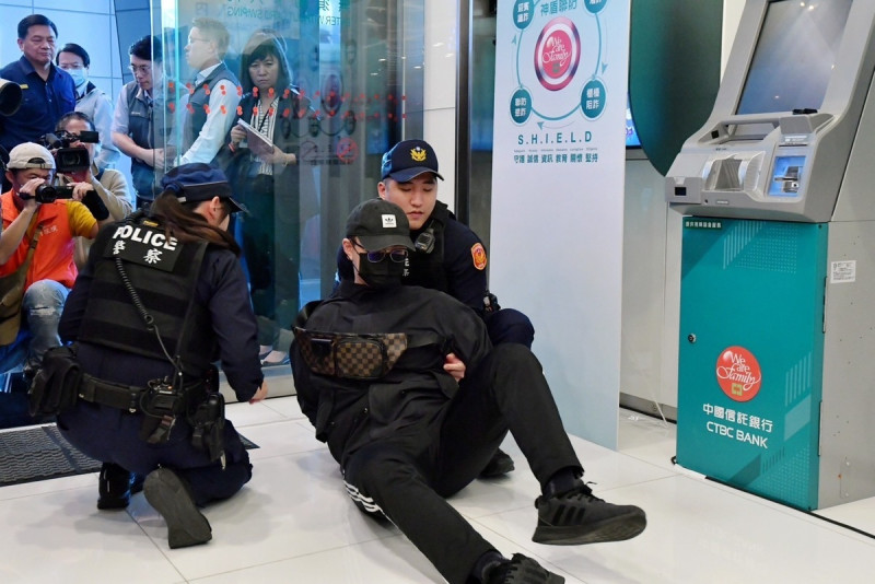模擬詐騙車手透過智能ATM領錢,觸動警局連線,由南港分局員警制服情境。 圖:行政院提供