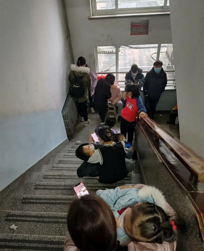 醫院樓梯間擠滿了排隊帶孩子看病的家長。   圖：翻攝自極目新聞