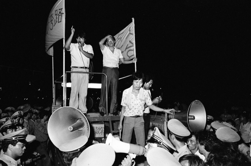 1987 年 9 月，蔡文旭參加江蓋世的台灣人走台灣路街頭演講，手拿麥克風的蔡文旭和洪茂坤遭到警方全面圍困，也毫無所懼。 圖：邱萬興攝影。 