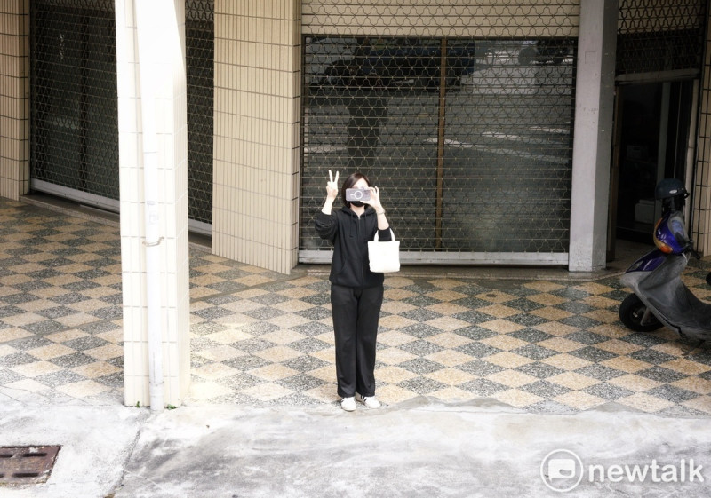 一位年輕的女性選民在賴清德掃街車隊經過時，邊拍照邊比出2號手勢。   圖：張良一/攝