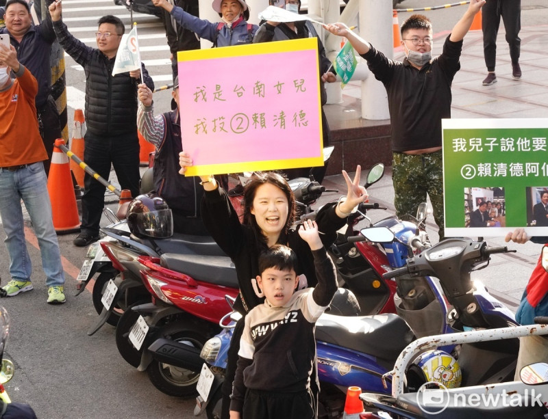 賴清德掃街車隊在台中市豐原區掃街拜票時，一位年輕媽媽帶著孩子，高舉票投賴清德的手舉牌，向賴加油打氣。   圖：張良一/攝