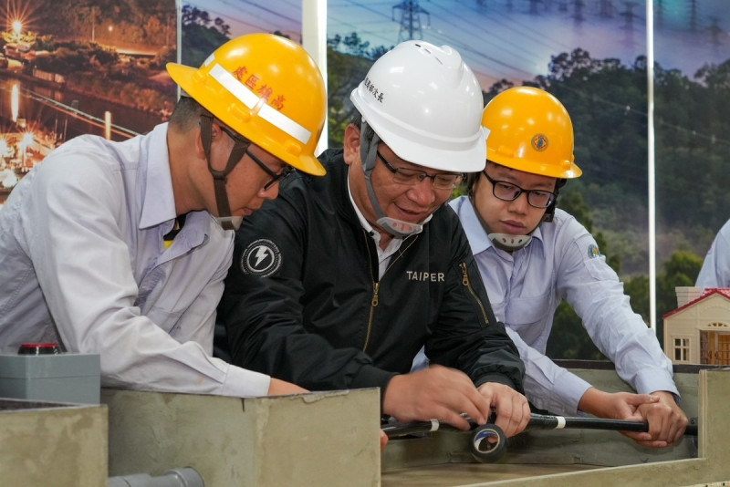 曾文生(中)體驗配電地下電纜壓接與絕緣處理作業。 圖:台電高雄區處/提供