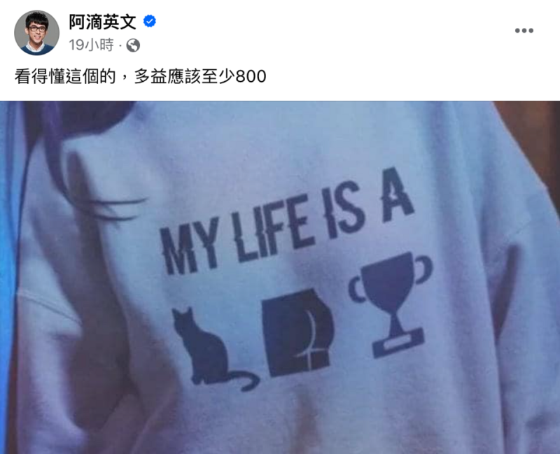 阿滴曬出一件上衣，上面寫有「MY LIFE IS A」（我人生是個）以及「貓咪、屁股、獎盃」3個圖示。   圖：翻攝自阿滴英文FB