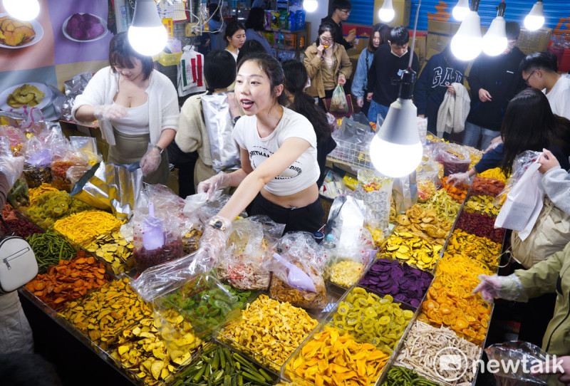 台北年貨大街賣年節應景甜食的工讀生賣力的向採購年貨的市民推銷他們的產品。   圖：張良一/攝