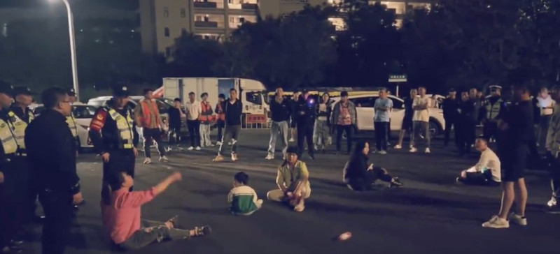 中國海南島遊客新年伊始從返鄉夢魘開展。有兩名抗議買不到輪渡票的女性遊客遭警察逮補，隔天其家屬全家大小盤坐在馬路中央抗議，   圖：取自「X」@YesterdayBigcat