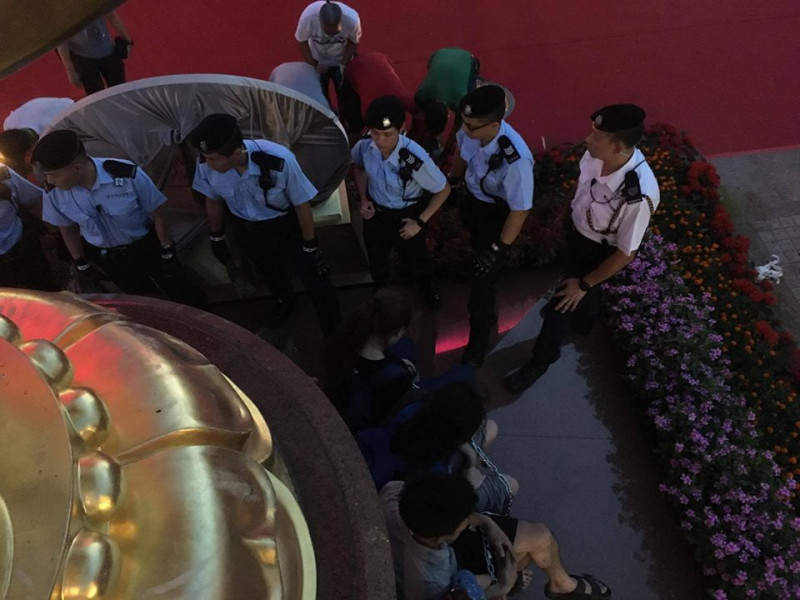 香港眾志、社民連及人民力量等組織成員今（28）日佔領香港灣仔金紫荊廣場，晚間遭到警方驅離逮捕。19:28 警方正重新接近紫荊銅像   圖：翻攝香港眾志臉書
