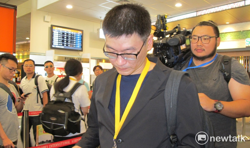 隨團出席雙城論壇的台北市議員梁文傑1日在松山機場檢閱相關政見。   圖：林朝億/攝