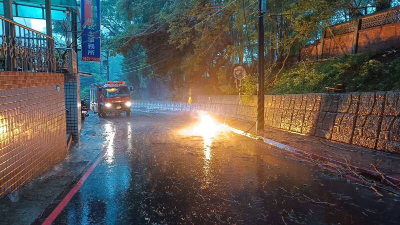 受到強風、強降雨影響，新北市淡水區新民街31日下午發生電纜線斷裂垂落、冒出火花等災情，警消到場管制。   圖：中央社/翻攝畫面