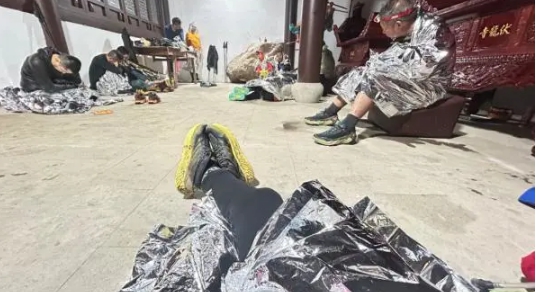 受困在寧波山中的江南百里馬拉松越野賽參賽者，在遇到雷暴受困寺廟後，披上防寒材料避免失溫。   圖 : 翻攝自澎派新聞