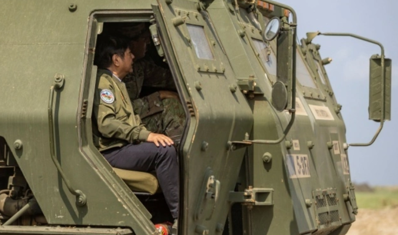 去年 4 月 26 日，菲律賓桑巴雷斯省，在菲律賓和美國啟動的「肩並肩『聯合軍演中，菲律賓總統馬可仕在一名美國士兵身邊視察了高機動性砲兵火箭系統。   圖：翻攝自澎派影像