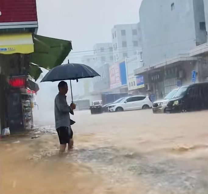 廣東中山淹水，民眾撐傘在水中前行。   圖：翻攝自掌聞視訊